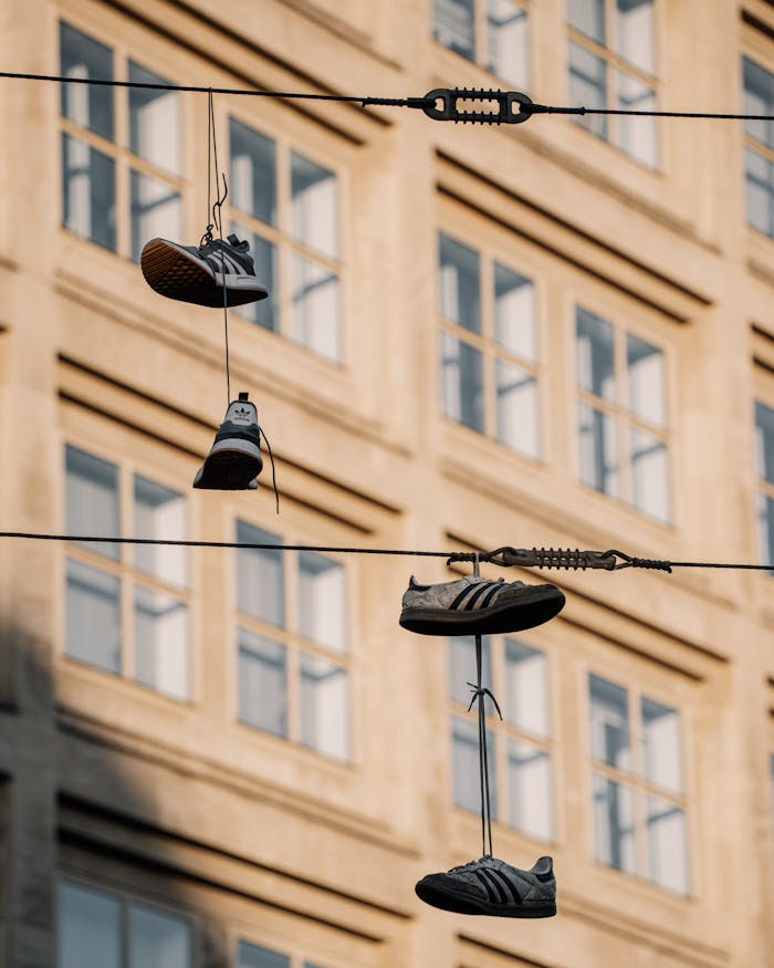 Casual sneakers dangle from power lines against a Berlin building backdrop.
